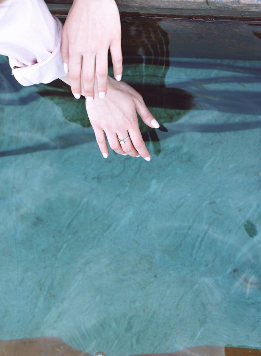 Two hands gently touching above still water, symbolising emotional clarity and connection, a moment where real life tarot could offer reflection and insight.