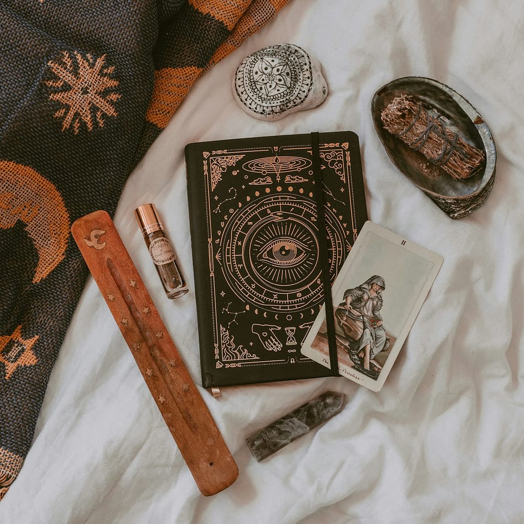 Tarot for clarity and healing through tarot tools: journal, Strength card, crystals, and incense used for guidance from tarot in a calming space.
