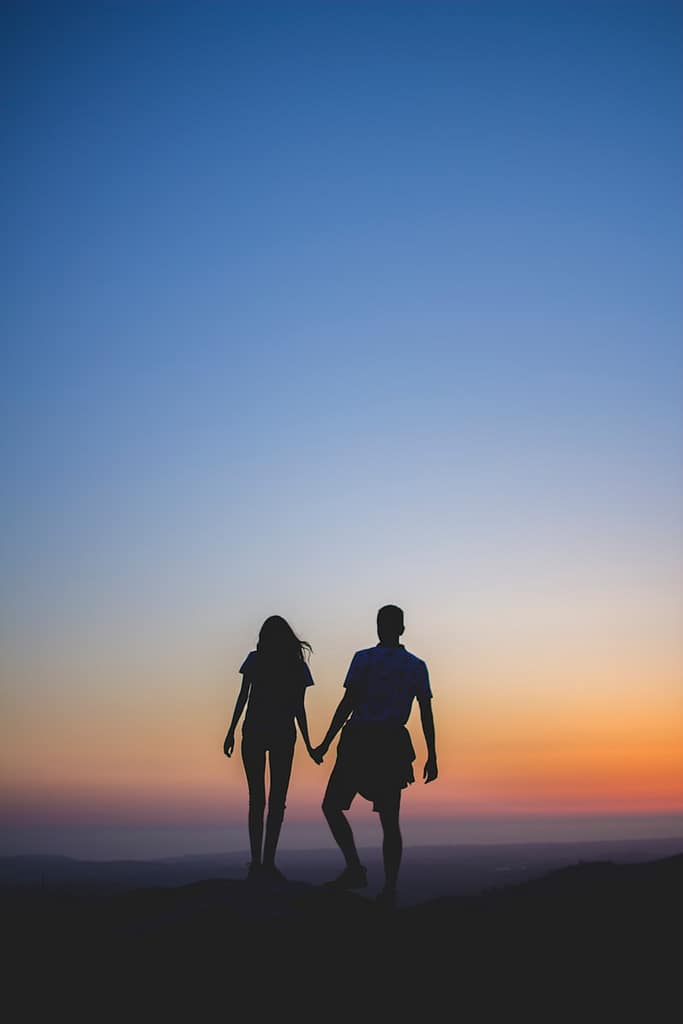 Silhouetted couple holding hands at sunset, symbolising deep connection and relationship clarity — a moment of guidance from tarot on love and intimacy.

