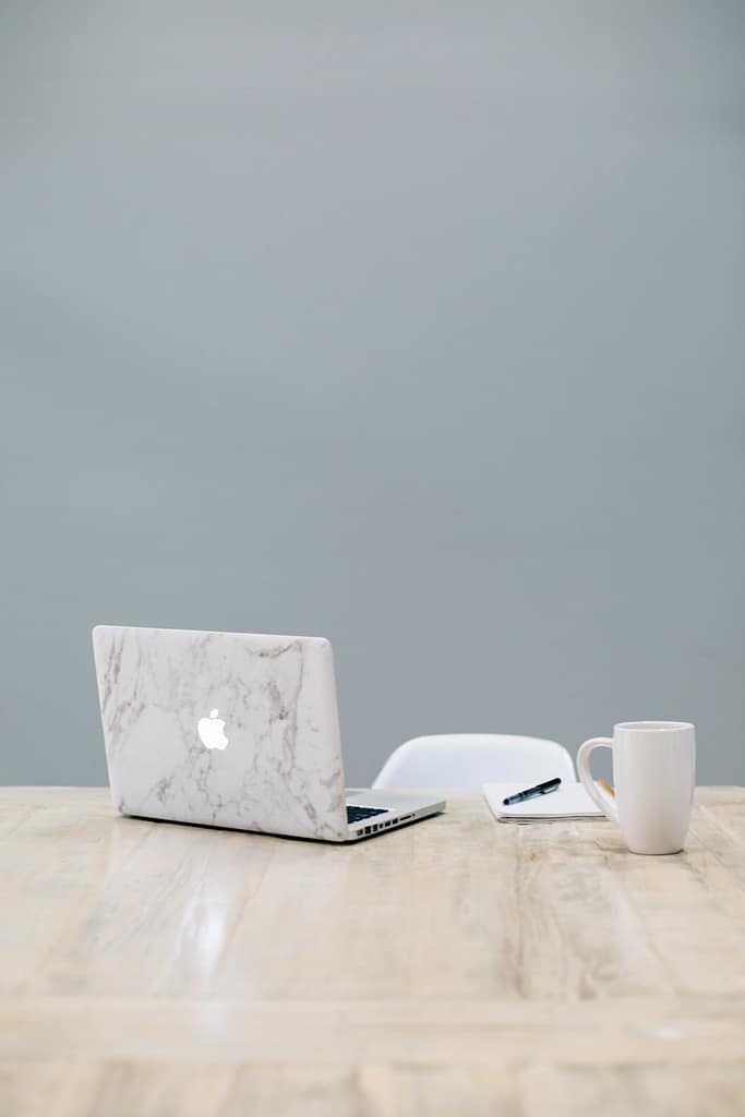 Laptop and mug on a wooden table, ready for an online tarot reading