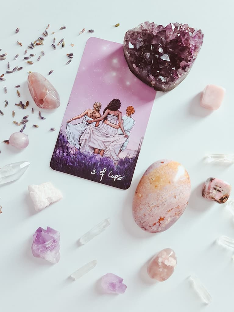 white and pink florals and a tarot card, showing a tarot reading for self.