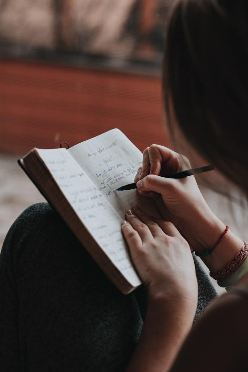 Person journalling in a notebook, representing open spiritual practices like journalling, meditation, and breathwork.