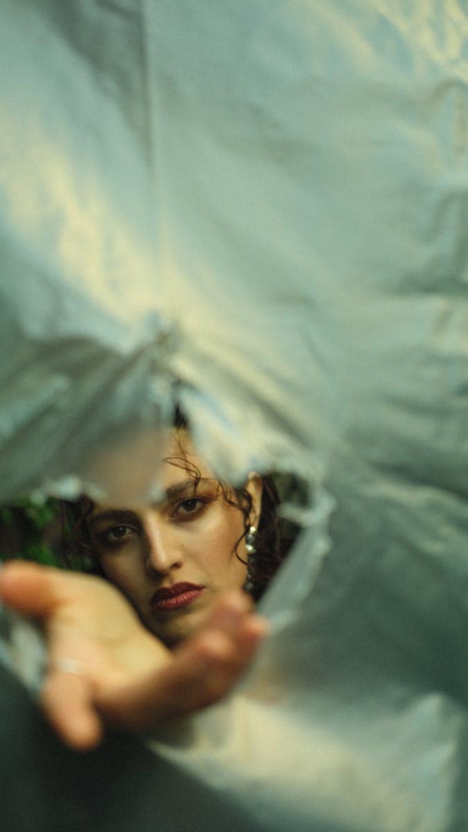 Symbolic image of a person reaching through a torn veil, representing the High Priestess tarot card’s themes of divine mystery and the veil of the temple.