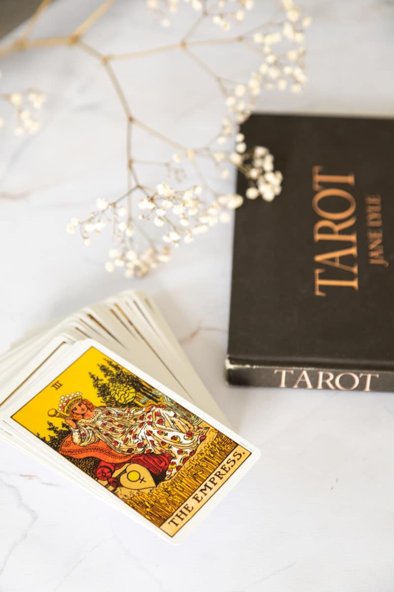 black and gold tarot book and tarot cards on white table