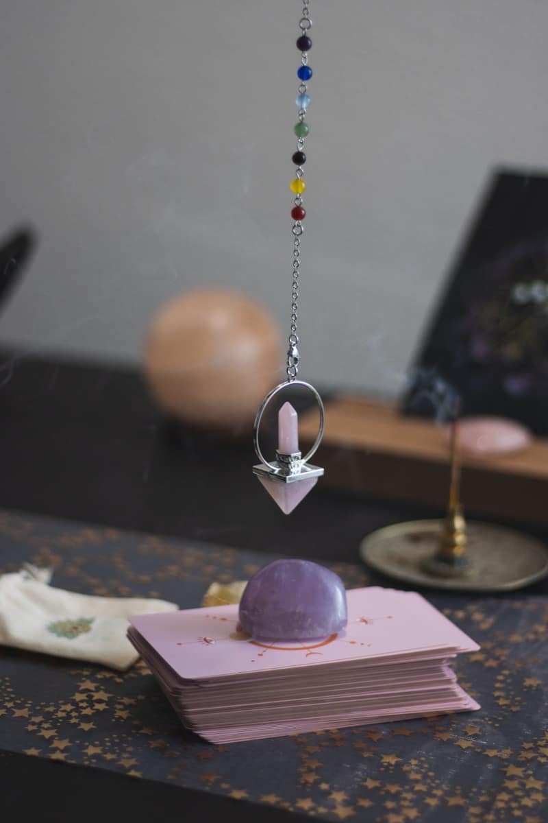 somebody using a pendulum with tarot cards.