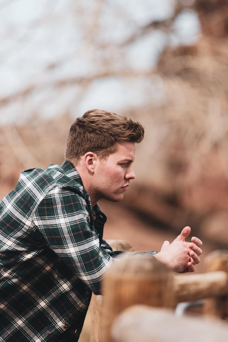 man in black white and gray plaid dress shirt holding smartphone