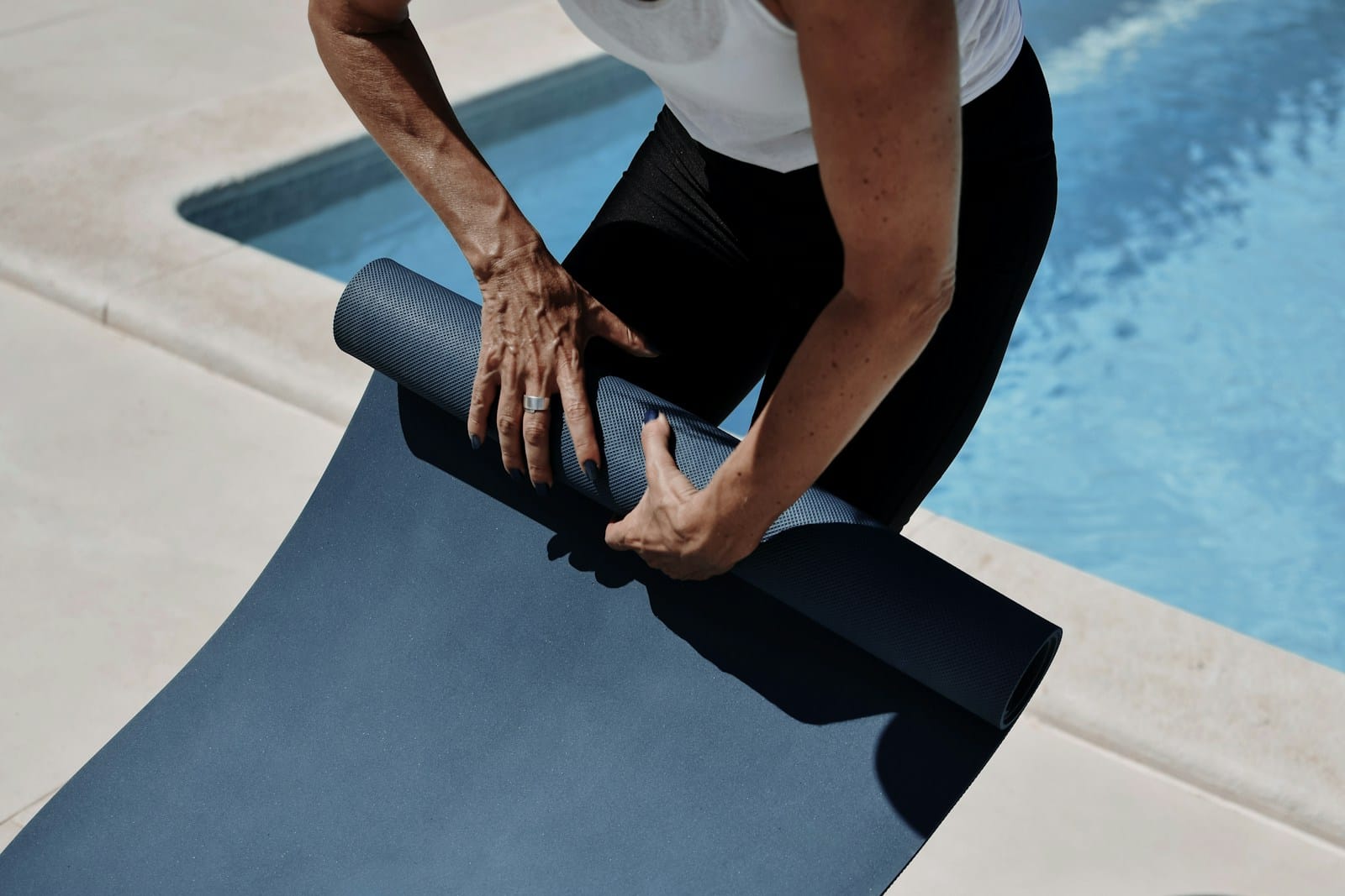 Person rolling up a yoga mat after class, reflecting on the types of yoga explained in this guide.