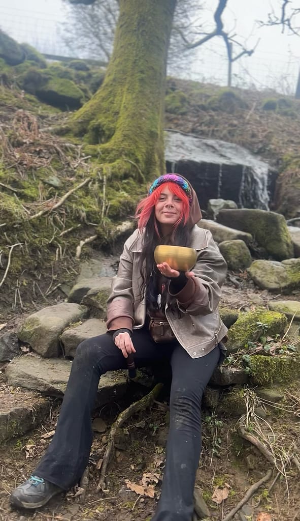 Healing Through Touch & Sound: Liv’s Holistic Approach 5 Liv holding a Himalayan singing bowl in the woods