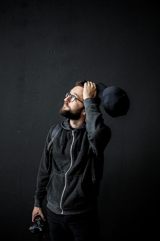 Man standing against a black wall, appearing deep in thought, representing the suit of Swords and the importance of mental clarity and self-awareness.
