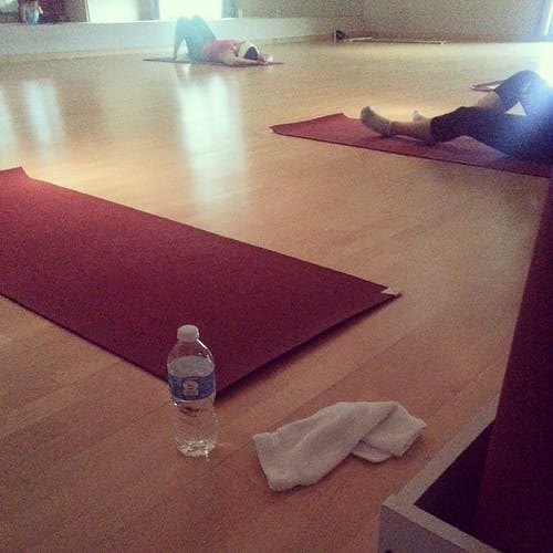 Yoga studio with red mats and students resting during one of the more restorative types of yoga classes.